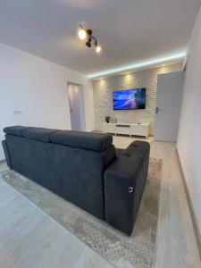 a large blue couch in a living room with a tv at Robert's White Apartament in Ploieşti