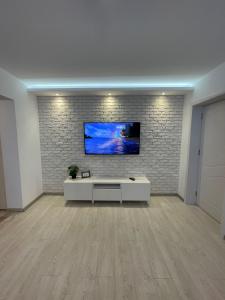 un soggiorno con una TV su un muro di mattoni di Robert's White Apartment a Ploieşti