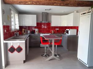- une cuisine avec des murs rouges, une table et des chaises rouges dans l'établissement Le Gîte de Martine et Marc, à Sazilly