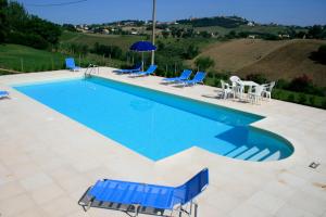 a large swimming pool with blue chairs and tables at Agriturismo Fara in Montegiorgio