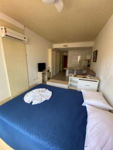 Una gran cama azul en una habitación con cocina en Flat Na Barra, en Salvador