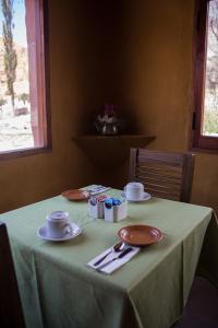 a table with a green table cloth and plates and cups at samaywasi in Purmamarca