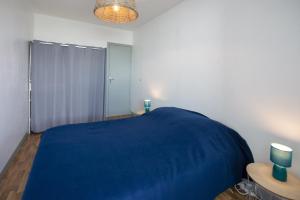een slaapkamer met een blauw bed en twee kaarsen op een tafel bij Venez profiter de ce bel appartement situe a Saint Hilaire de Riez in La Parée Preneau