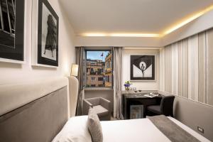 ローマにあるコンドッティ パレスのベッドとデスクが備わるホテルルームです。