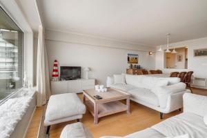 ein Wohnzimmer mit einem weißen Sofa und einem Tisch in der Unterkunft Kindvriendelijk app met frontaal zeezicht &garage in Koksijde