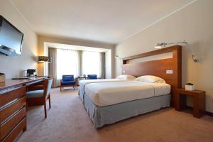 a hotel room with a large bed and a desk at Tivoli Coimbra Hotel in Coimbra