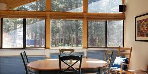 een eetkamer met een tafel, stoelen en ramen bij Bright & Airy Condo, Sleeps 4 - Creekside #103 in Bear Valley