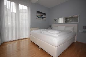 a white bed in a white bedroom with white curtains at Berlin Habitat in Berlin