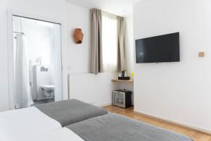 a white bedroom with a bed and a flat screen tv at Hotel Palm - Astotel in Paris