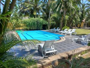 a swimming pool with lounge chairs and a swimming pool at Jim's Beach Villas in Hikkaduwa +13 photos