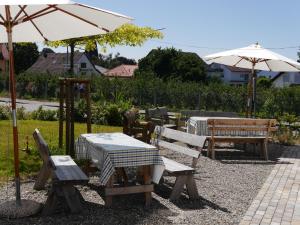 un patio con mesas, sillas y sombrillas en Pension & Café Schlupfwinkel en Salem