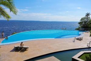 a large swimming pool with a view of the ocean at Tropical Executive Flat Vista Maravilhosa do Rio in Manaus +8 photos