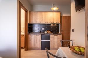 a kitchen with wooden cabinets and a table with a bowl of fruit at Τrilogy Studios in Syvota