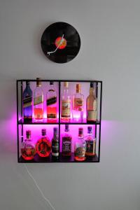 a shelf with bottles of alcohol and a clock on a wall at Folitsa a Lovely central House in Kos Town