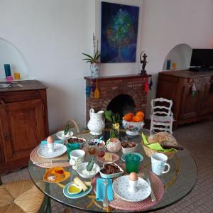 a glass table with food on it in a room with a fireplace at Chambres d'Hôtes Couleurs d'Elvine in Coutances