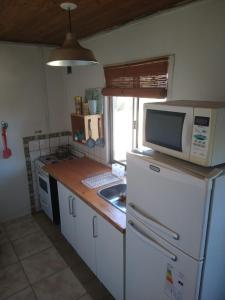 a kitchen with a white refrigerator and a microwave at La Escondida. Hasta p /6 personas. Parrilla. WiFi in Puerto Pirámides