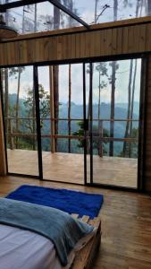 ein Schlafzimmer in einem Baumhaus mit einem großen Fenster in der Unterkunft Latibule Glamping in La Vega