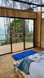 a bedroom with a bed and large glass windows at Latibule Glamping in La Vega