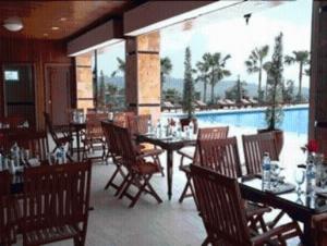 a restaurant with tables and chairs and a pool at Royal Senyiur Hotel in Prigen