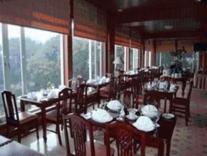 a dining room with tables and chairs and windows at Royal Senyiur Hotel in Prigen