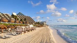 a beach with umbrellas and chairs and the ocean at Paradisus Cancun All Inclusive in Cancún
