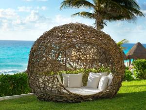 a rattan bed in the grass near the ocean at Paradisus Cancun All Inclusive in Cancún