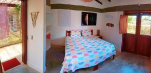 a bedroom with a bed with a colorful comforter at Pousada Casa de João Kitehouse in São Miguel do Gostoso