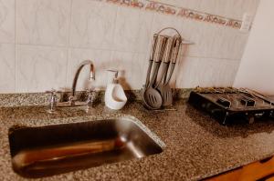 a kitchen counter with a sink and utensils at Hakuna Matata in Malargüe