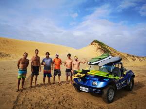 a group of men standing next to a car in the desert at Pousada Casa de João Kitehouse in São Miguel do Gostoso