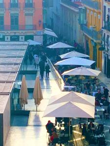 a group of people sitting at tables with umbrellas on a street at Apartment en Rambla in Alicante