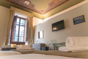 Coco Places Soggiorno Panerai, Centro Storico في فلورنسا: غرفة نوم بسريرين وتلفزيون في السقف