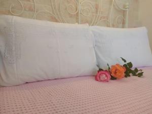 ein Bett mit zwei Kissen und zwei Blumen drauf in der Unterkunft Eleana Studios in Ampelas