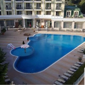 a large blue swimming pool with an umbrella in front of a building at Апартаментен Комплекс Сплендид - Студио Афродита, № 113 in Varna City +1 photo