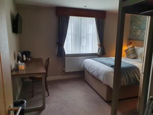 a bedroom with a bed and a desk and a window at Old Swan in Skipton