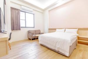 a white bedroom with a bed and a chair at WOW Penghu Homestay in Magong