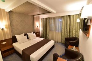 um quarto de hotel com uma cama e uma televisão em Hotel Forum em Ploieşti