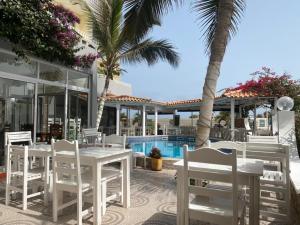 um pátio com mesas e cadeiras brancas e uma piscina em Hotel NHATERRA em Santa Maria