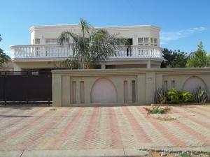 a white house with a balcony on top of it at Carlcyn Homestay in Gaborone