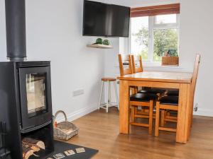 a living room with a fireplace and a table and a stove at Lowenek in Bodmin