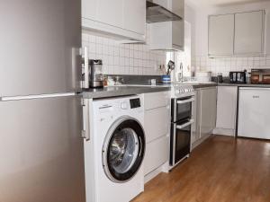 a white kitchen with a washing machine in it at Lowenek in Bodmin