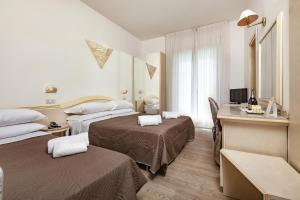 a hotel room with two beds and a desk at Ariminum Hotel in Rimini