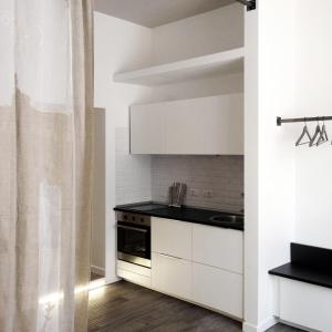 cocina con armarios blancos y encimera negra en Trastevere Residence, en Roma