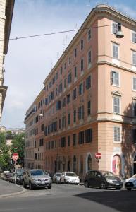 un gran edificio de ladrillo con coches estacionados frente a él en Trastevere Residence, en Roma