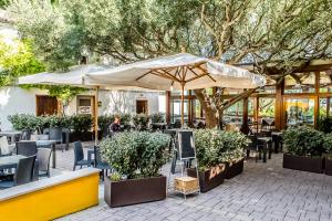 un patio con mesas, sillas y una sombrilla en Camping Village Internazionale en Sirolo