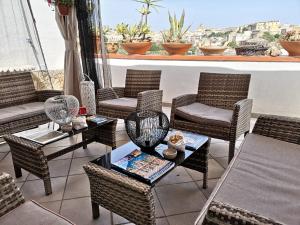 a patio with wicker chairs and tables on a balcony at Villa Ambra B&B in Noto