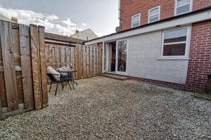a patio with a table and chairs next to a fence at Guest Homes - Watledge House Apartment in Tewkesbury