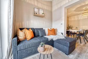 a living room with a blue couch and a table at Guest Homes - Watledge House Apartment in Tewkesbury