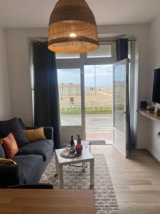 トゥルヴィル・シュル・メールにあるParadis les pieds sur le sable trouville palaceのソファとテーブルのあるリビングルーム