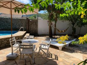 un patio con mesa, sillas y sombrilla en Almas gêmeas quarto casal en Angra dos Reis