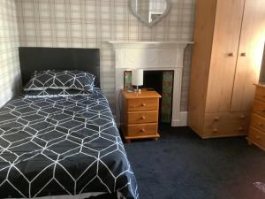 a bedroom with a bed and a dresser and a fireplace at The Glenwood in Torquay